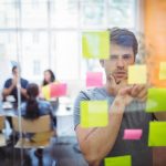 Close-up of male executive reading sticky notes in office