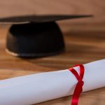 Close-up of graduation certificate with mortar board on a table